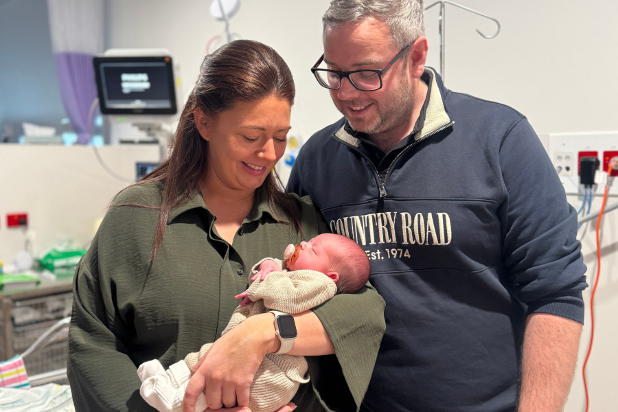 Two parents holding a baby in their arms,